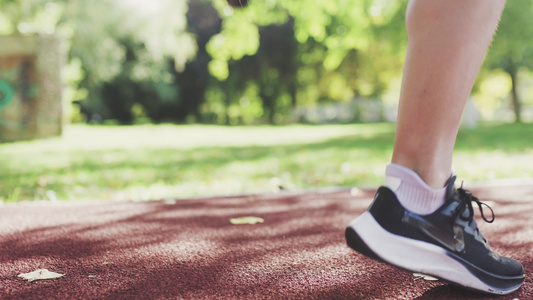 健身跑步女孩在公园的全天候合成跑道表面上热身原地跑视频