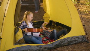 女孩少年从露营帐篷内的男孩少年手中拿吉他十几岁的女孩12秒视频