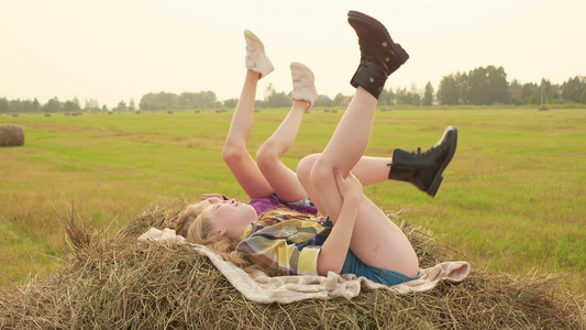 女孩少年躺在干草堆上摇摆着双腿快乐的少女在秋天的干草堆视频