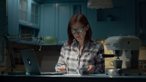 30多岁的年轻女子戴着眼镜晚上在蓝色厨房的家里用笔记本电脑34秒视频