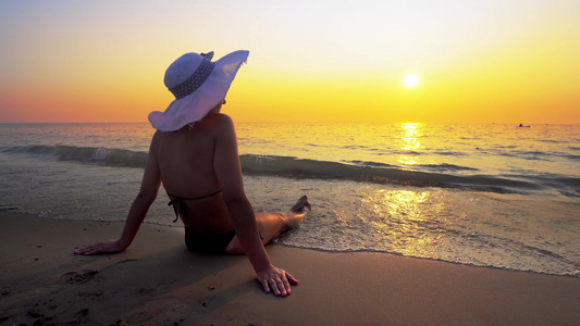 日落时在海滩上坐着的西班牙女人视频