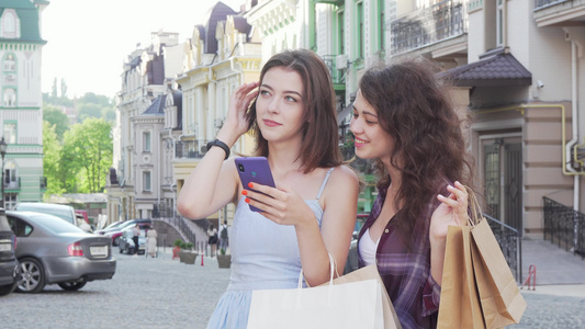 两名年轻女性朋友使用网上地图在城市街道智能手机上使用视频