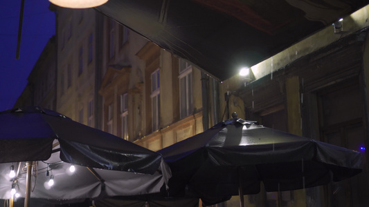 欧洲老城街露天咖啡厅的树冠顶上下倾盆大雨夜里在暴雨视频