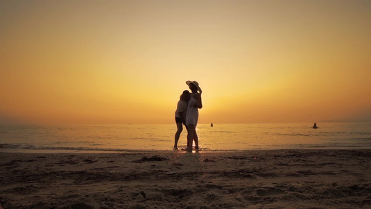幸福的情侣在日落时分在沙滩上玩耍男人抱着一个穿着白色视频