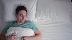 年轻人躺在床上熟睡着躺在他的背上他在睡眠中受到干扰30秒视频