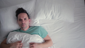 在白色床上的年轻男人不睡不着只看一个点28秒视频