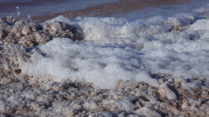 白泡沫和黑海河口底和河口岸的盐晶体24秒视频