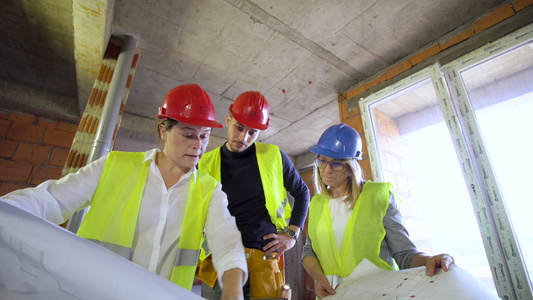 工程师建筑师和建筑工地工人拿着示意图和谈话视频