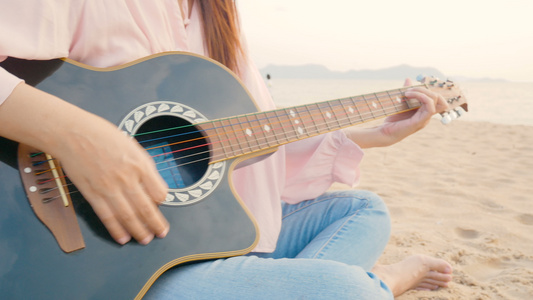 4k关闭长发女长发女郎在海滩弹声吉他日落时风温柔感觉视频