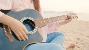 4k关闭长发女长发女郎在海滩弹声吉他日落时风温柔感觉9秒视频