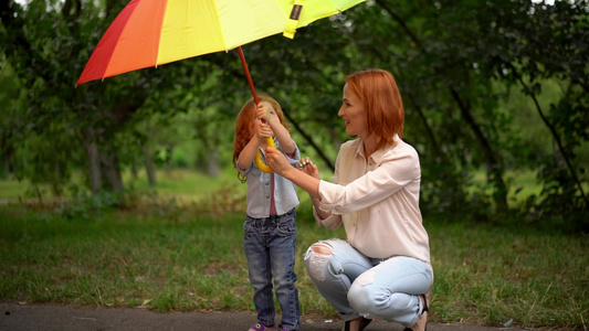 母亲和女儿站在彩虹雨伞下视频