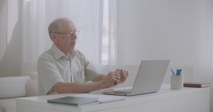老年男性律师通过互联网咨询客户使用带网络相机的笔记本电脑16秒视频