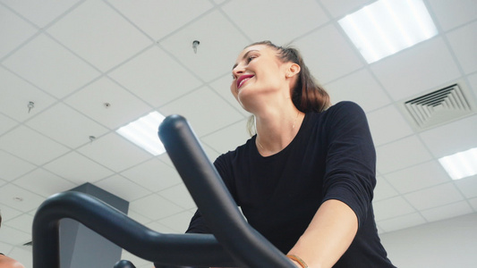 微笑的女人在健身房的自行车课上训练室内自行车快乐的视频