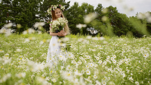 微笑的年轻女孩在花圈与鲜花花束站在开花的领域美丽的14秒视频