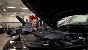 迷人的女汽车修理工对镜头微笑在车库工作9秒视频