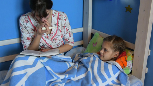 妈妈坐在床上给一个生病的孩子读一本书视频