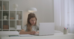 女学生在家在线学习在抄写本上写字听写用笔记本电脑听21秒视频