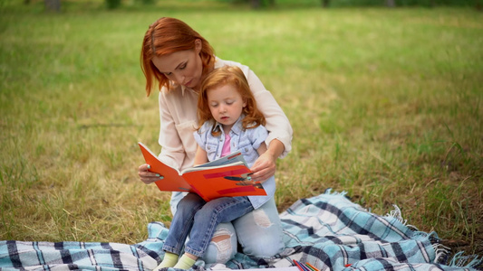 妈妈在公园里和女儿一起读一本书视频