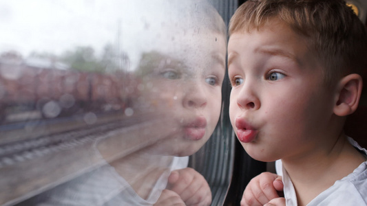 在下雨的天气下看着火车窗外的好奇男孩视频