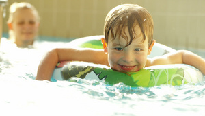 快乐的小男孩游泳在泳池里戴橡皮环13秒视频