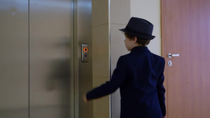 小男孩看起来像一个商人穿着西装和帽子在办公室等电梯22秒视频