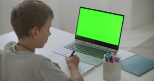 小男孩正坐在桌边画画笔记本电脑边电脑绿幕16秒视频