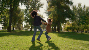 微笑的母亲和女儿一起玩耍在绿色的春天公园田野上跳舞19秒视频