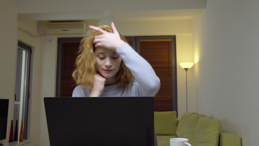 可爱的女孩坐在客厅的桌子上在笔记本电脑前喝咖啡在家视频