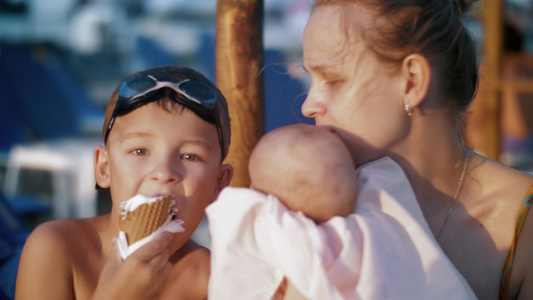 在海滩男孩吃冰淇淋时生着孩子的妈妈和大儿子视频