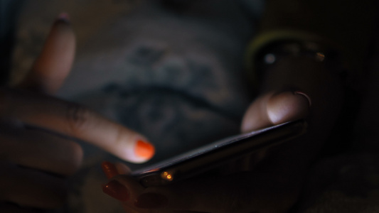 在黑暗中使用智能手机的女黑客放松娱乐和技术概念视频