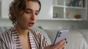 惊讶的女人穿着睡衣在家里使用智能手机阅读信息25秒视频