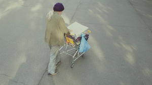 流浪老人在街上推着购物车靠近长凳21秒视频
