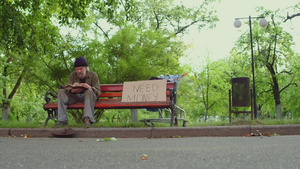 无家可归的人坐在长凳上手拿着书28秒视频