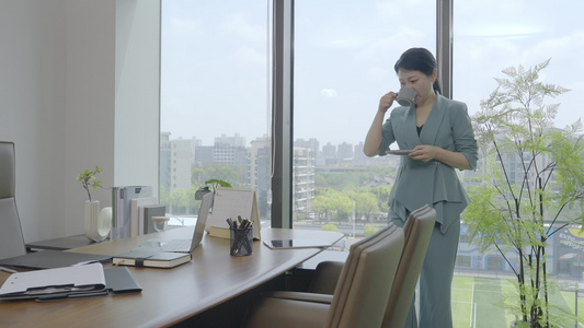 办公室女领导喝咖啡后使用平板电脑办公视频