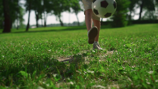 活跃的男孩在绿草上踢球视频