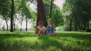 笑的孩子们坐在绿色公园的树下26秒视频