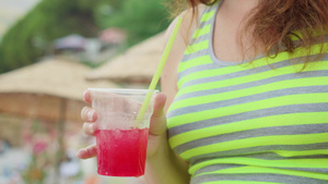 女孩在阳光明媚的白天握着红鸡尾酒与冰块16秒视频