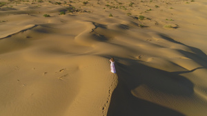 年轻的孤独女子留着长发穿着白色连衣裙走在沙漠中的米色16秒视频