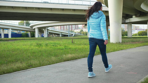 穿着牛仔裤和蓝色夹克的年轻女子在高速公路背景的现代24秒视频