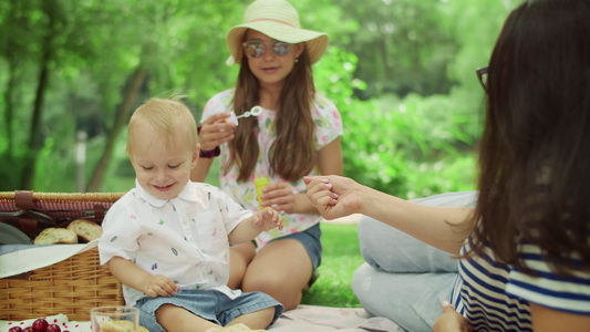 妇女、幼儿和孩坐在公园的毯子上视频