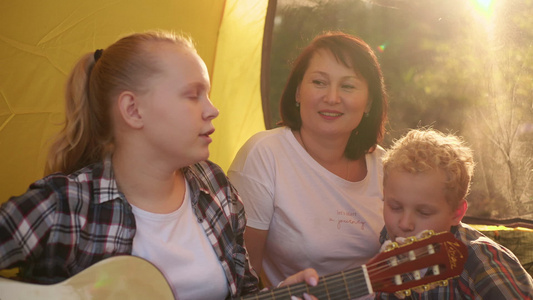 有两个孩子坐在帐篷里享受吉他和两个孩子的幸福家庭视频