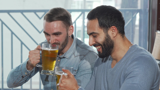 快乐的男性朋友搭着啤酒杯享受在酒吧喝酒视频