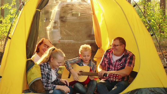 快乐的旅游家庭在阳光明媚的森林露营帐篷里玩得开心友好视频