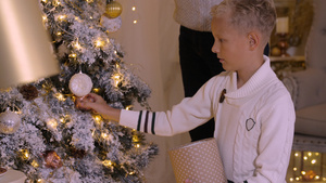 快乐的少年男孩在家中用玻璃玩具和园林装饰圣诞树10秒视频