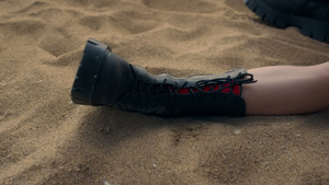 苗条的双腿迷人的女孩穿着黑色靴子躺在黄色的海滨沙滩上22秒视频