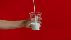 妇女用手把牛奶倒入空塑料杯的宽视镜12秒视频
