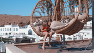 快乐的女孩在度假酒店的吊椅上用手机放松在避暑胜地阳光明媚16秒视频