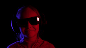 戴着黑色太阳镜和耳机在黑色工作室听音乐的少女11秒视频