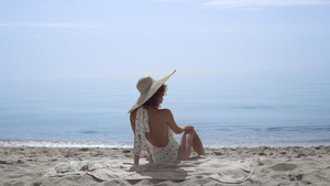 诱人的女人坐在沙滩上穿着泳装在美丽的海浪前14秒视频