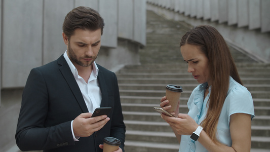商务男性女性在街头喝咖啡处理手机文件视频